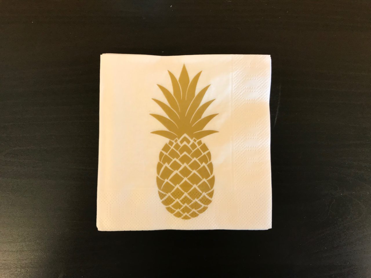 Golden Pineapple Party Napkin On A Black Table