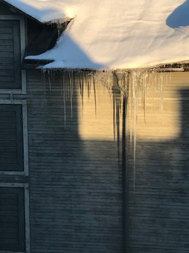 Roof With Snow And Icicles Hanging Down From The Gutter