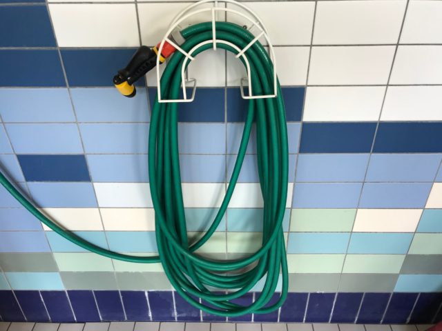 Rolled Up Water Hose Mounted On Wall Holder