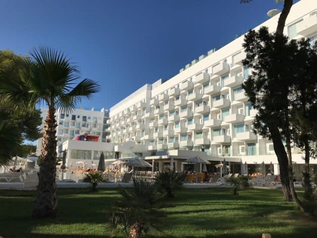 White Hotel With Symmetric Balconies And Green Lawn