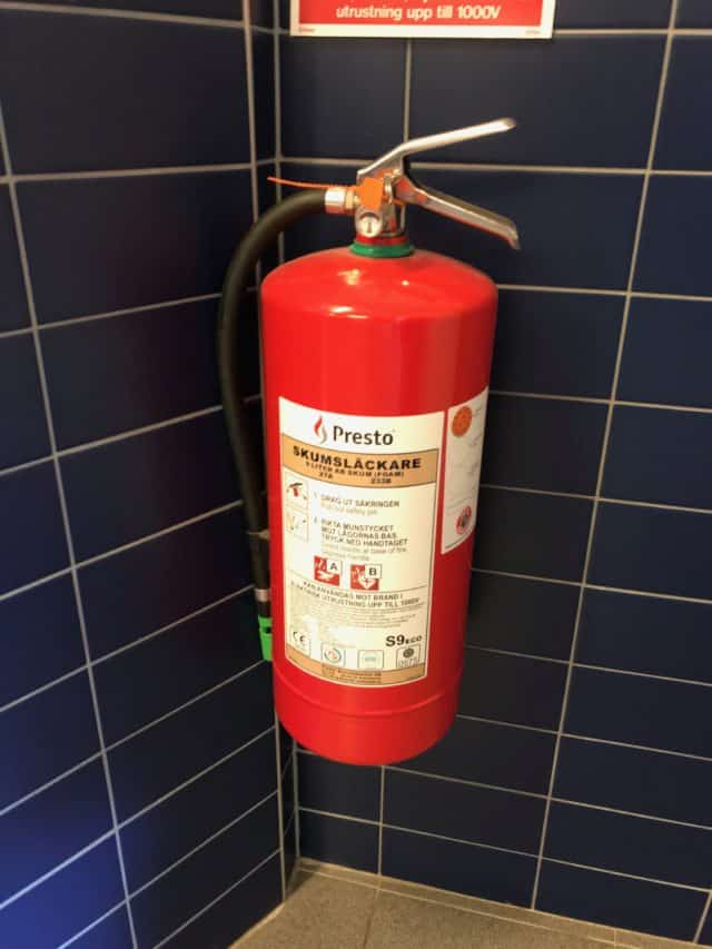 Red Fire Extinguisher Hanging On Tiled Wall