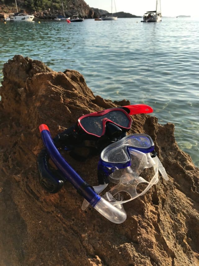 Snorkeling Gear On A Cliff By The Ocean With Boats