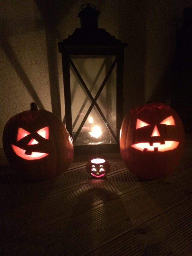 Scary Pumpkins And A Little Cute Pumpkin In The Dark On Halloween With Lighted Tealights In