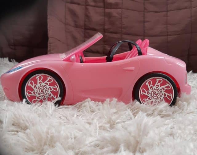 Pink Barbie Convertible Car From The Side On White Carpet With Brown Background