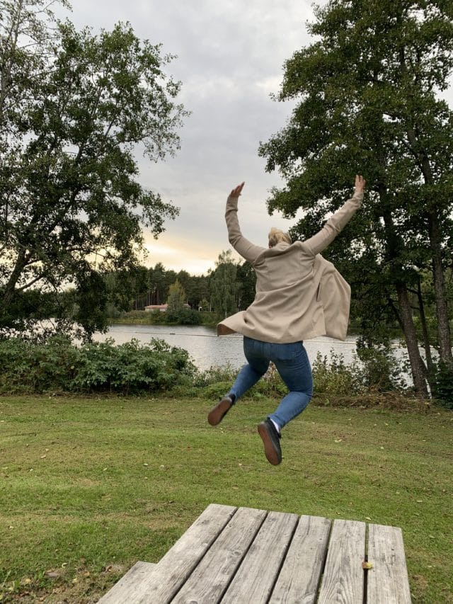 Woman In Beige Jacket Jumping Off A Wooden Table