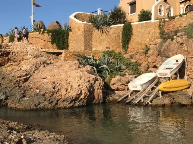 House On A Cliff With Boats And A Flag Pole