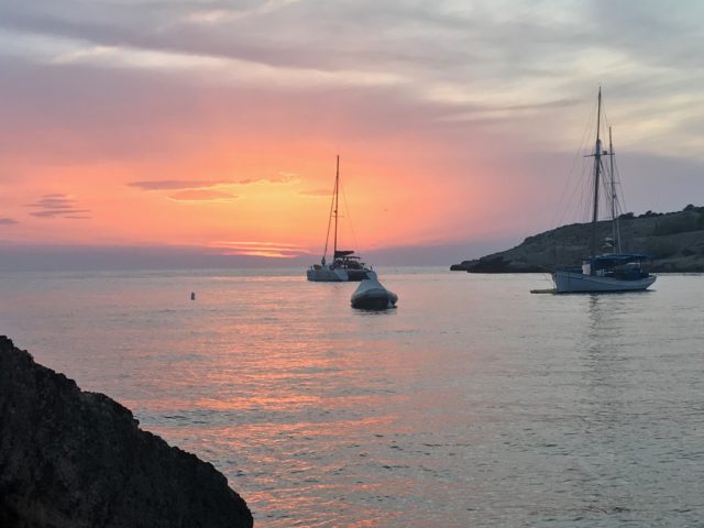 Sunset In Ibiza With Sail Boats In A Cove