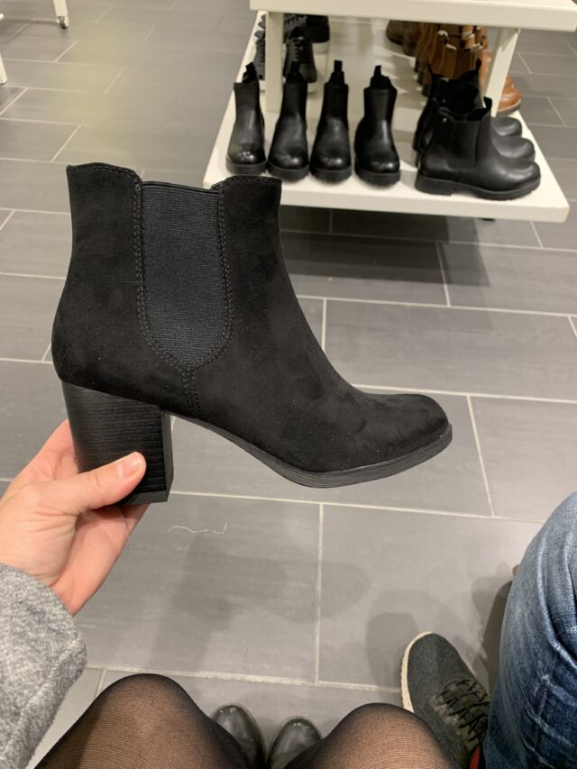 Woman Holding A Black Boot In Her Hand In The Shoe Store