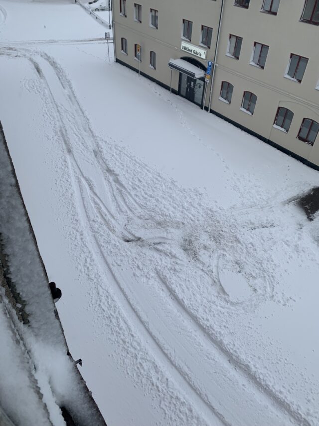 Car Tracks In The Snow Between Buildings