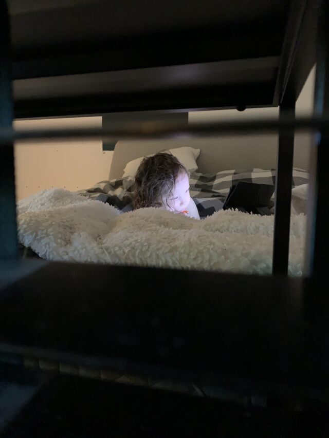 Kid Watching A Movie On A Table In Bed