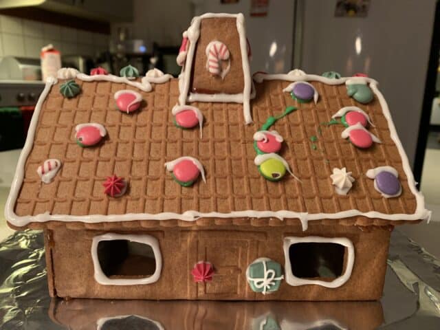 Homemade Gingerbread House With Candy And Frosting In Kitchen