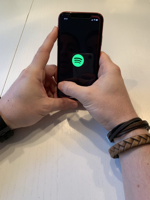 Man Holding iPhone With Spotify Logo With Bracelets On His Arm