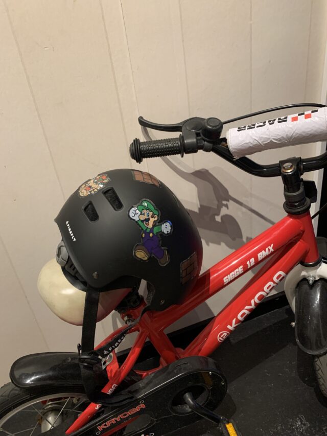 Red Kid BMX Bike With A Helmet On It