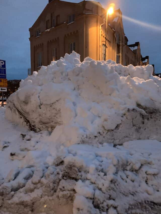 Pile Of Snow In Front Of Old Brick Building And Street Light
