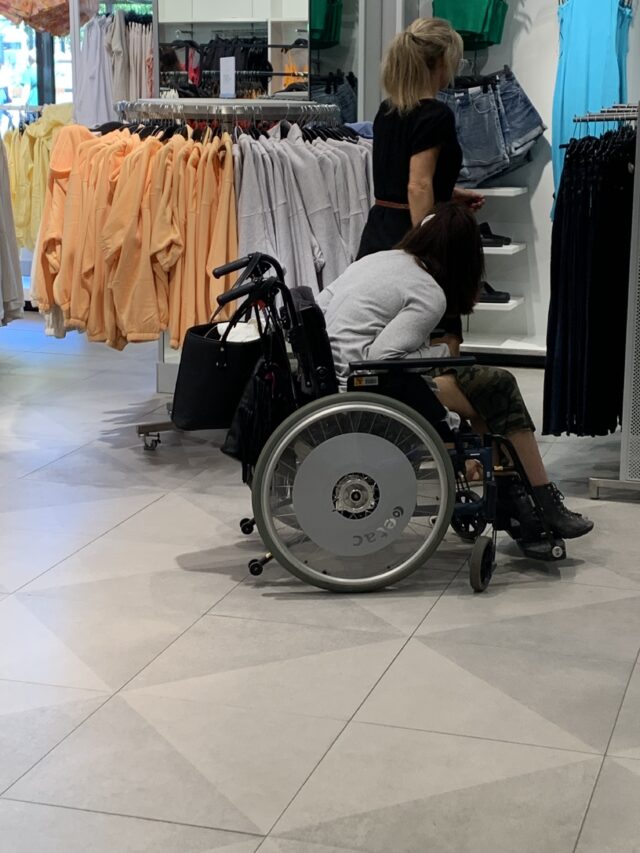 Person In Wheelchair And Assistant Shopping In Store