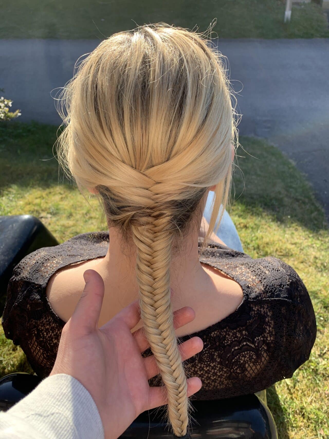 Hand Holding Braid On Blond Woman In Black Lace Top