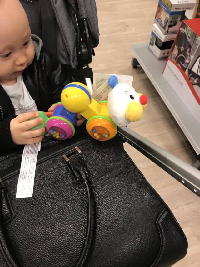 Baby Holding A Colorful Toy Caterpillar While Sitting In a Pram